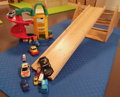 Bunte Spielzeugautos flitzen die Holzrutsche hinunter