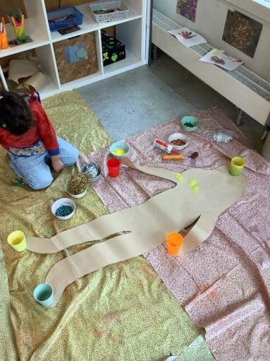 Ein Kind bastelt an einer Papierversion von sich selbst herum