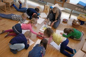 Im Kindergarten: Kinder sitzen auf dem Boden und malen mit Wasserfarben