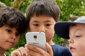 drei Kinder schauen auf Smartphone