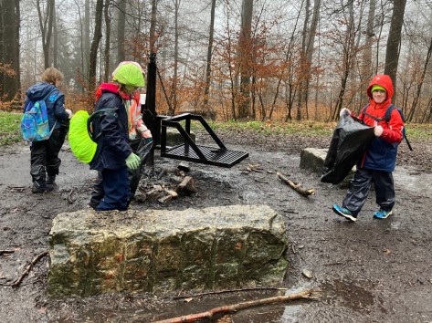Das Bild zeigt Schulkinder, die beim Waldputztag Müll einsammeln.