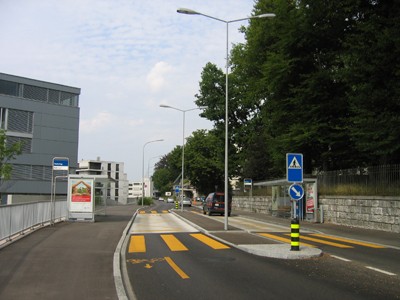 Haltestelle Hürlimannplatz. Haltestelle in Kernfahrbahn mit Mittelinsel (asphaltiert), Fahrbahn im Haltebereich aus Beton.