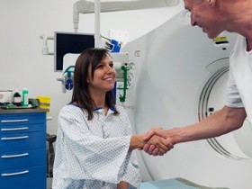 Vorbereiten einer Patientin für die CT-Untersuchung. Im Hintergrund das CT-Gerät.