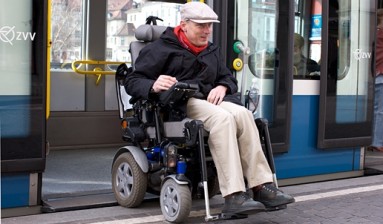 Ein Herr, der mit dem Rollstuhl ins Cobratram einsteigt. 