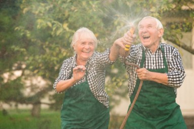 Seniorenpaar spritzt mit Wasserschlauch herum