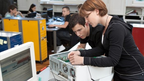 Mädchen und Junge betrachten das Innere eines PCs.