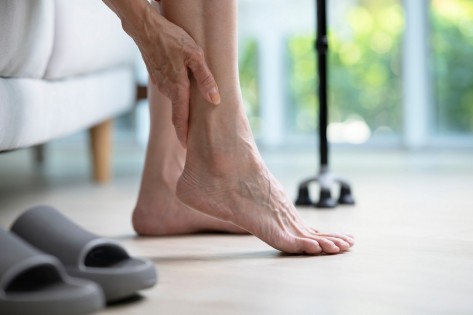 Foot pain concept, senior woman suffering from pain in ankle at home. woman rubbing, massaging sore feet area of pain, Mature woman discomfort painful feet ache from walking..