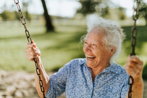 Cheerful senior woman on a swing at a playground