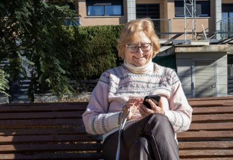 Ältere Dame auf der Bank am Smartphone