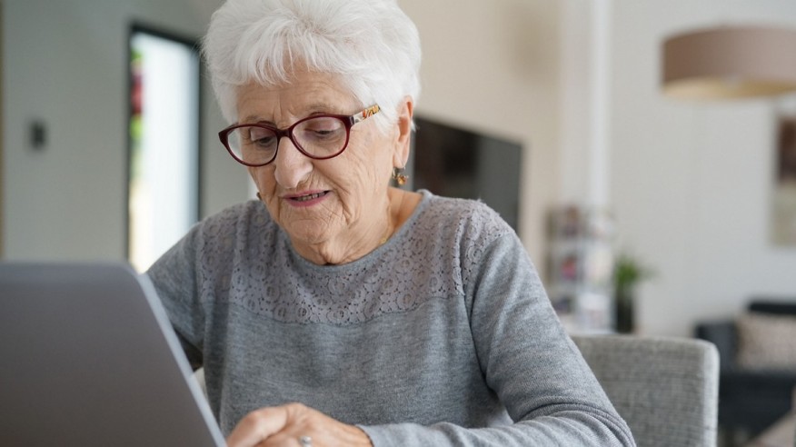 Seniorin sitzt am Computer in ihrem Zuhause.
