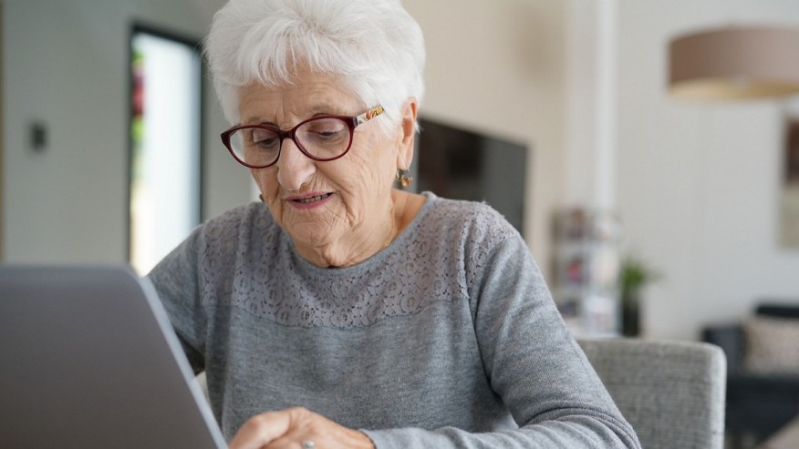 Seniorin sitzt am Computer in ihrem Zuhause.