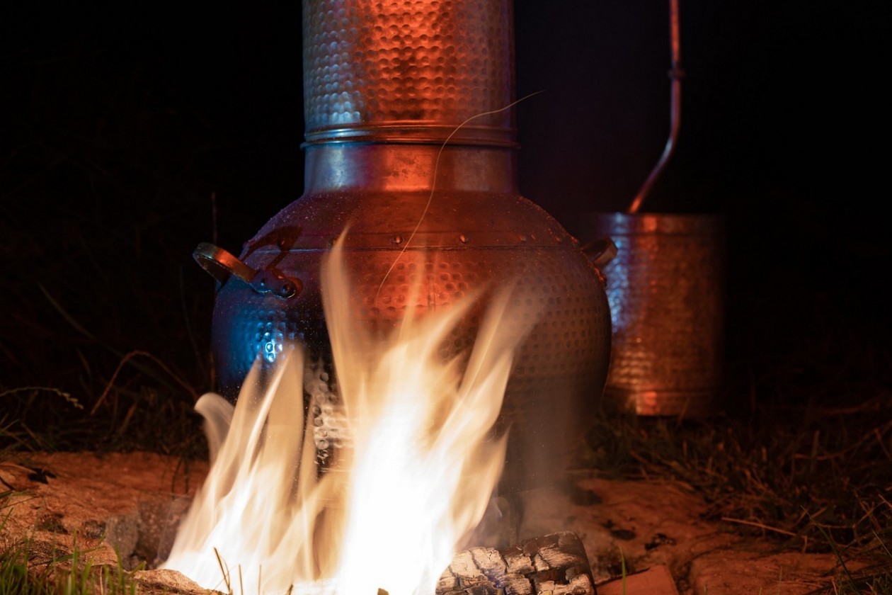 Ein Destilliergerät hängt über einem Feuer.