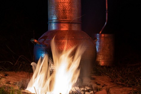 Ein Destilliergerät hängt über einem Feuer.