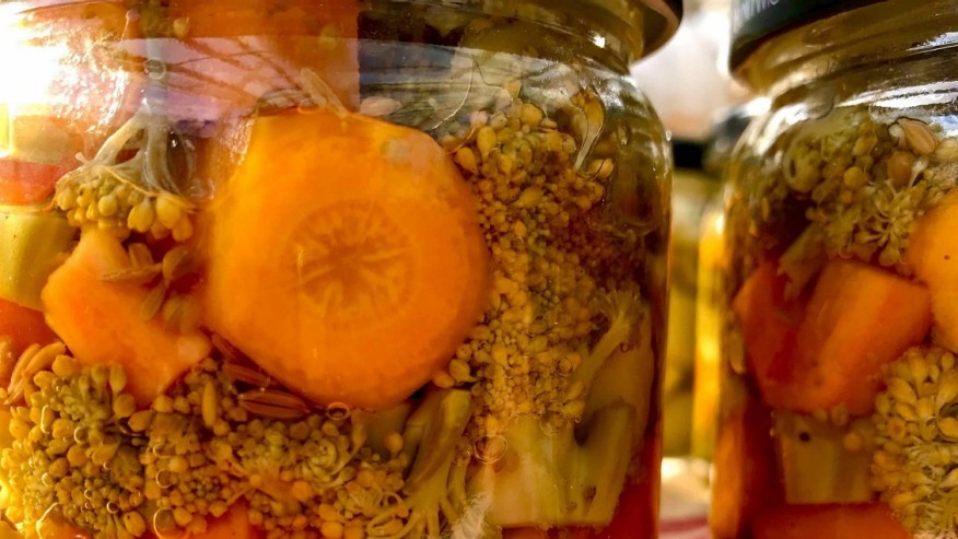 Zwei Einmachgläser gefüllt mit in Essig eingelegten Karotten und Broccoli.