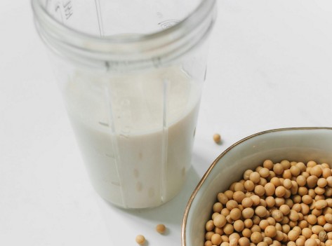 Ein Messbecher mit Sojamilch und eine Schale mit Sojabohnen.