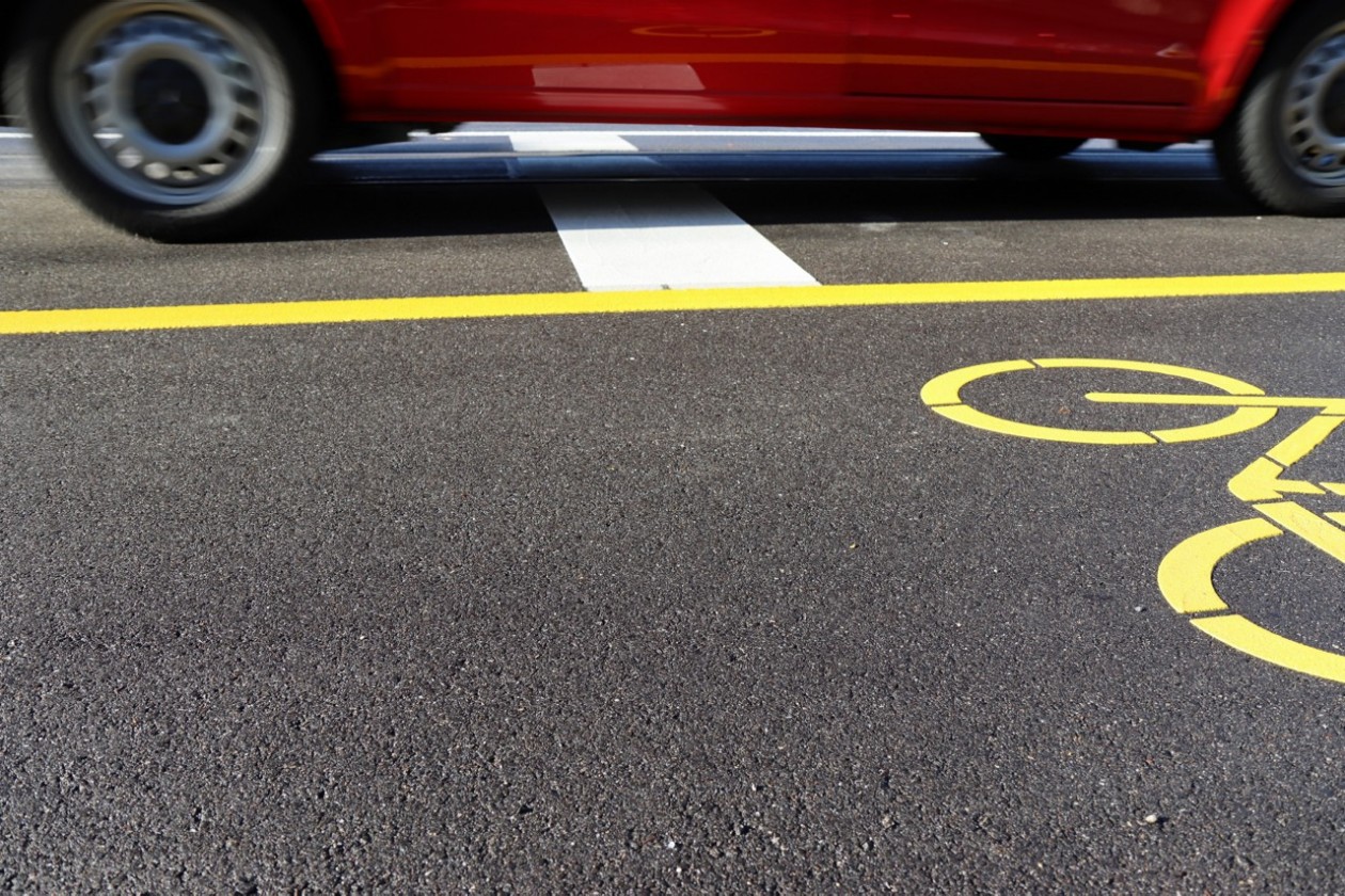 Unterer Teil eines vorbeifahrenden Autos mit leichter Bewegungsunschärfe auf einem lärmarmen Strassenblag.