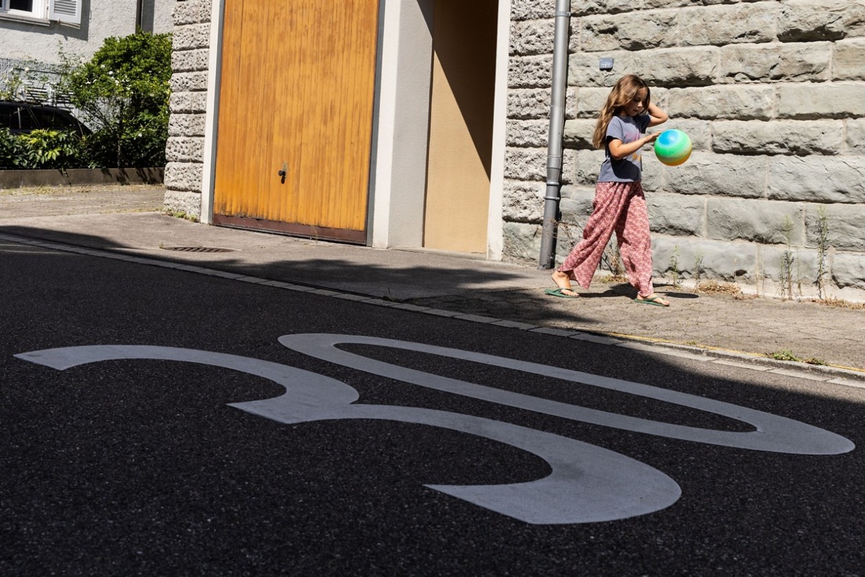 Mädchen mit einem Spielball auf dem Trottoir in einer Tempo-30-Zone.