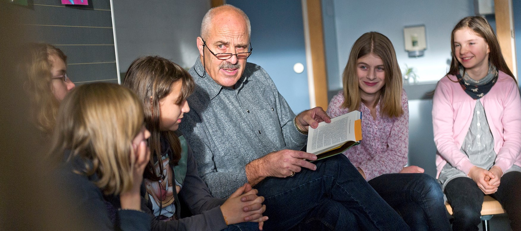 Ein Senior liest Kindern aus einem Buch vor.