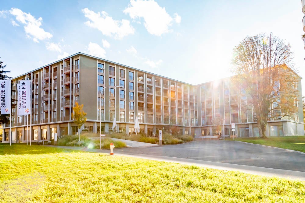 Modern anmutendes Gebäude, umgeben von Rasen und einigen Bäumen