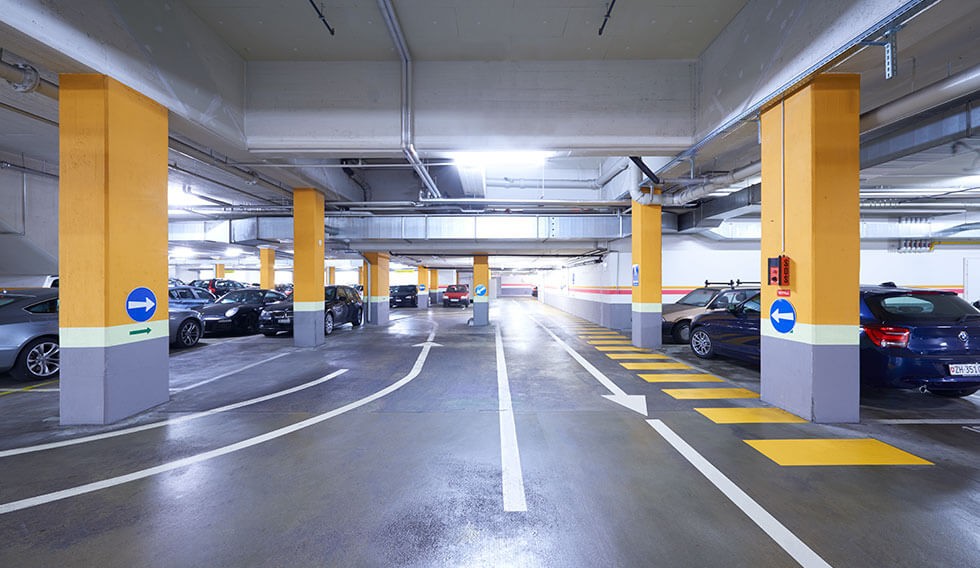 Parkplätze in einem Parkhaus mit weissen Markierungen auf dem Boden und gelben Säulen. Bild: zVg