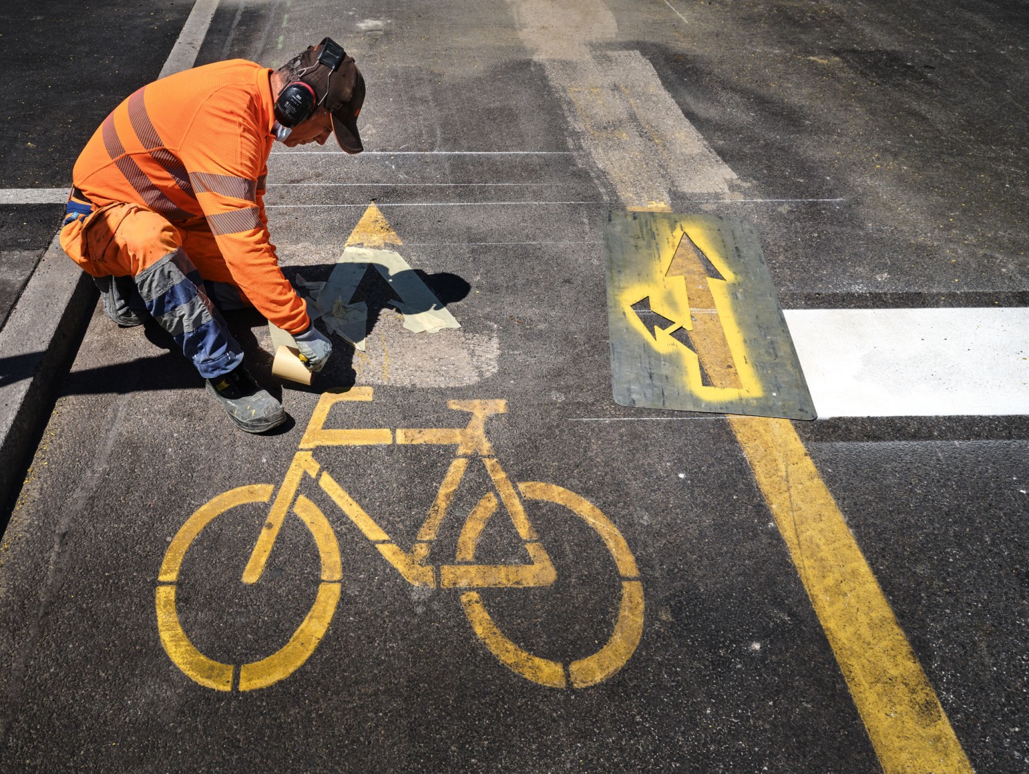 Bauarbeiter markiert ein gelbes Velopiktogramm