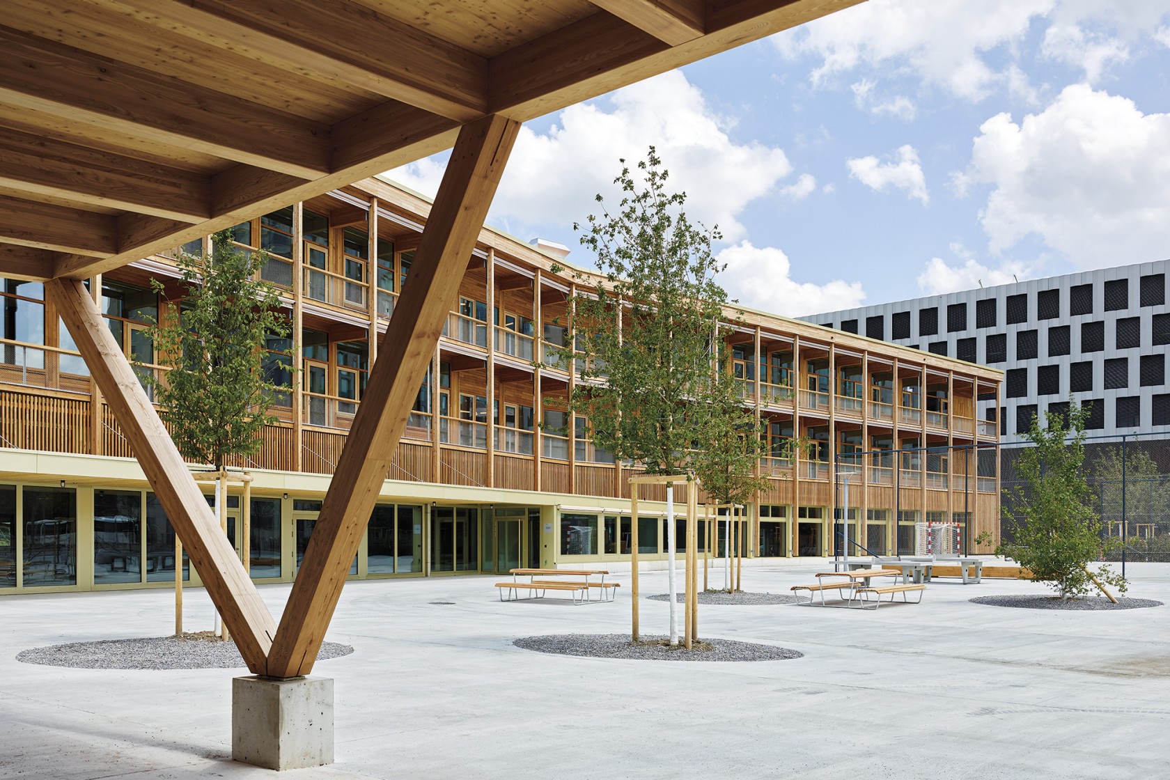 Das Foto wirft einen Blick vom Quartierpark auf die Holzfassade der Schulanlage.