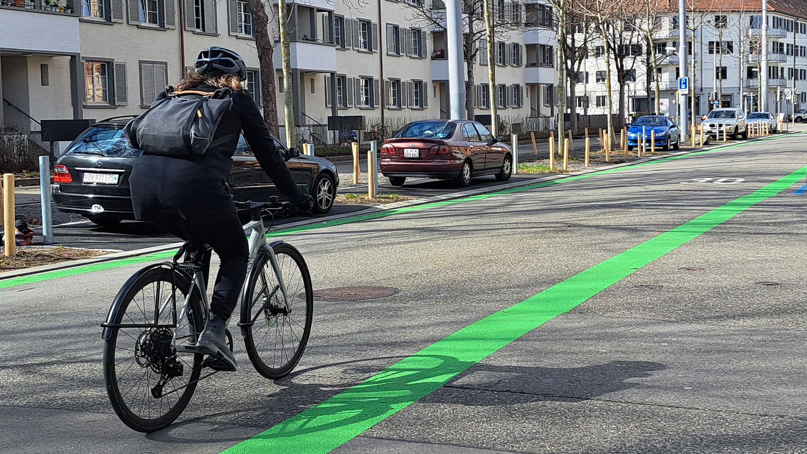 Eine Velofahrende auf einer Strasse, welche links und rechts ein grünes Band markiert hat. 