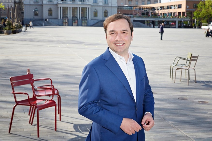 Podcast Marco Radojevic Marco Radojevic Projektleiter Projektstab Stadtrat in blauem Blaiser mit weissem Hemd auf Sechseläutenplatz vor dem Opernhaus.