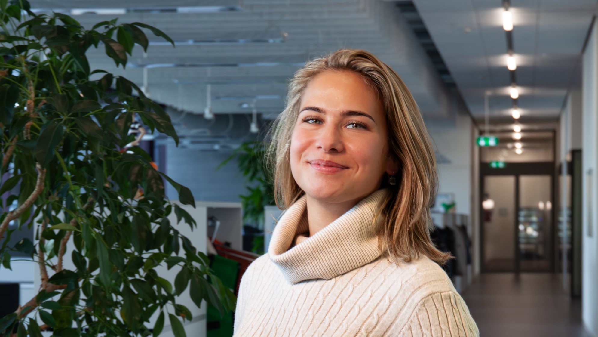 IT-Spezialistin im Gang der OIZ stehend mit Laptop in der Hand.