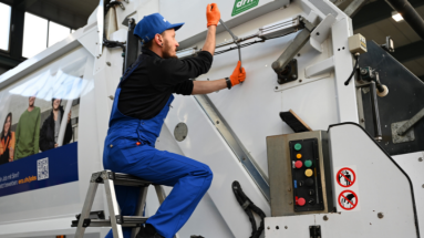 Autmobilmechatroniker in blauer Arbeitskleidung bei der Arbeit an einem Nutzfahrzeug für Abfall