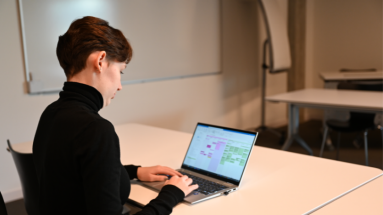 Kauffrau in scharzem Rollkragenpulli bei der Arbeit am PC in einem Schulungsraum