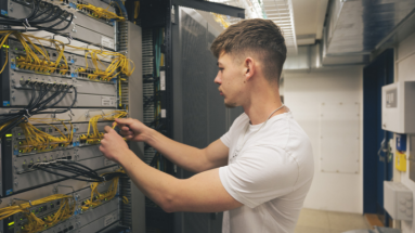 Plattformentwickler in weissem T-Shirt bei der Arbeit in Serverraum.