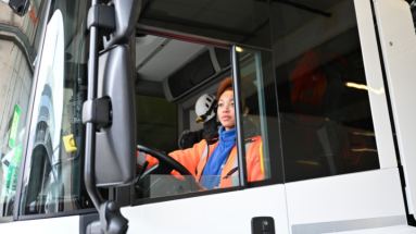 Strassentransportfachfrau in oranger Arbeitskleidung in Lastwagen sitzend