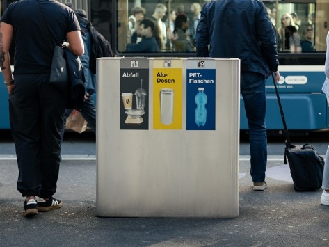 Das Bild zeigt einen Recyclingbehälter in der Bahnhofstrasse in Zürich. Der Behälter hat einen Einwurf für Alu-Dosen, für PET-Flaschen und für Abfall.