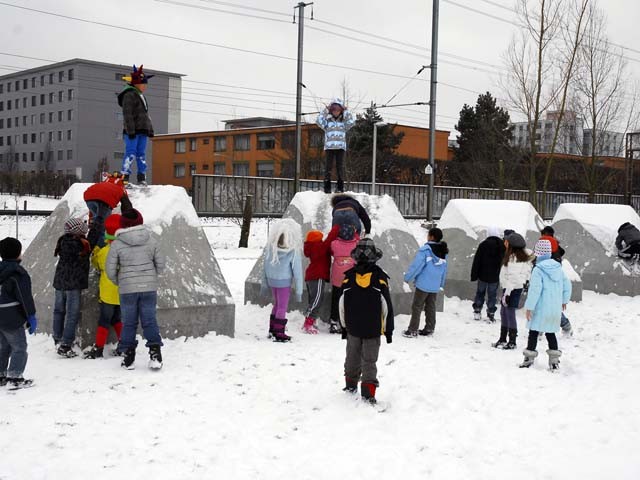 Kinder spielen im Schnee und auf den Betonblöcken von Olivier Mosset