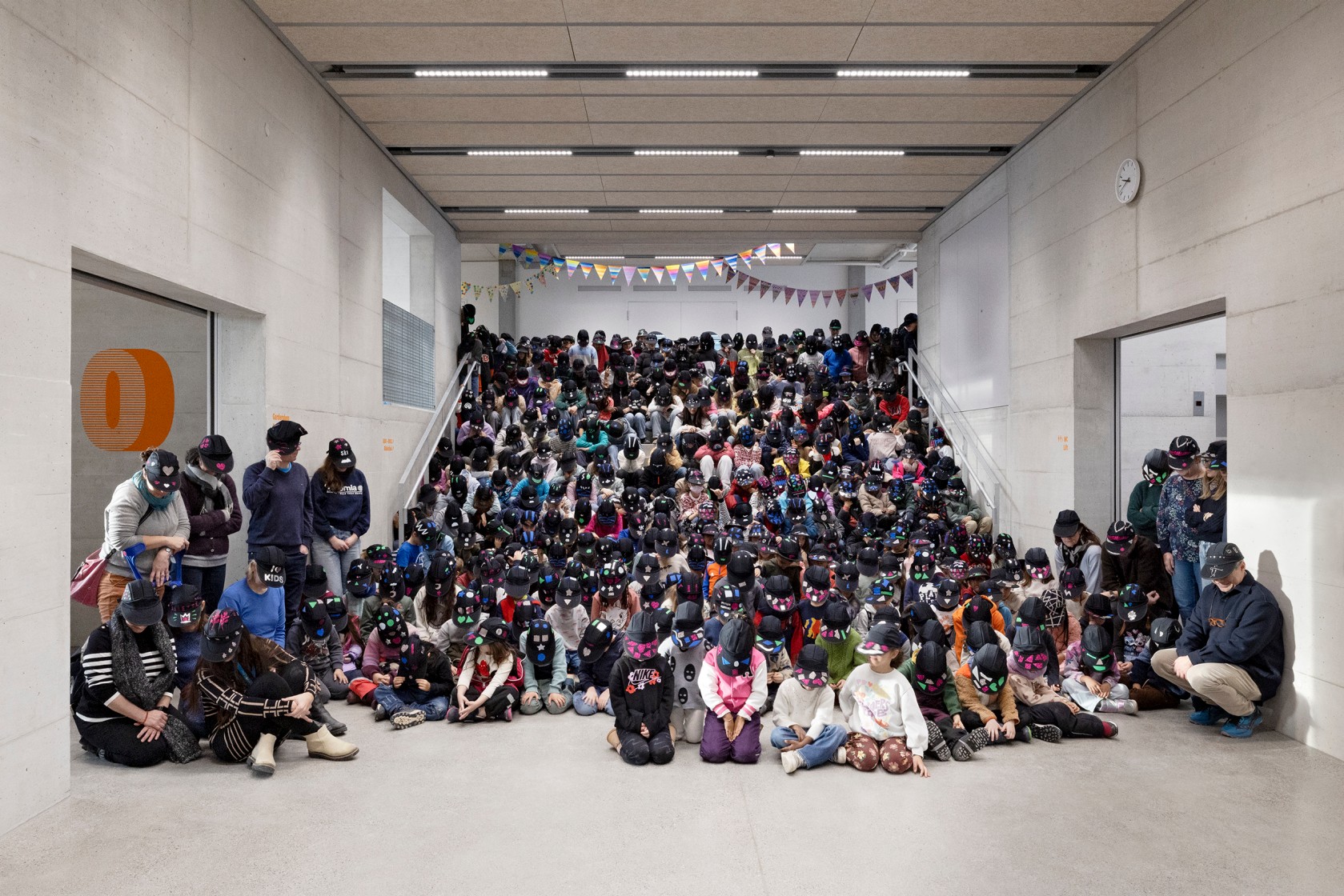 Kinder, sitzend im Treppenhaus, mit schwarzen Caps, die das Gesicht verdecken