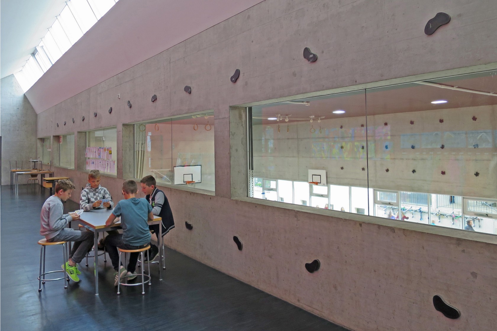 Vier Schüler jassen vor einer Betonwand mit Stahlfiguren