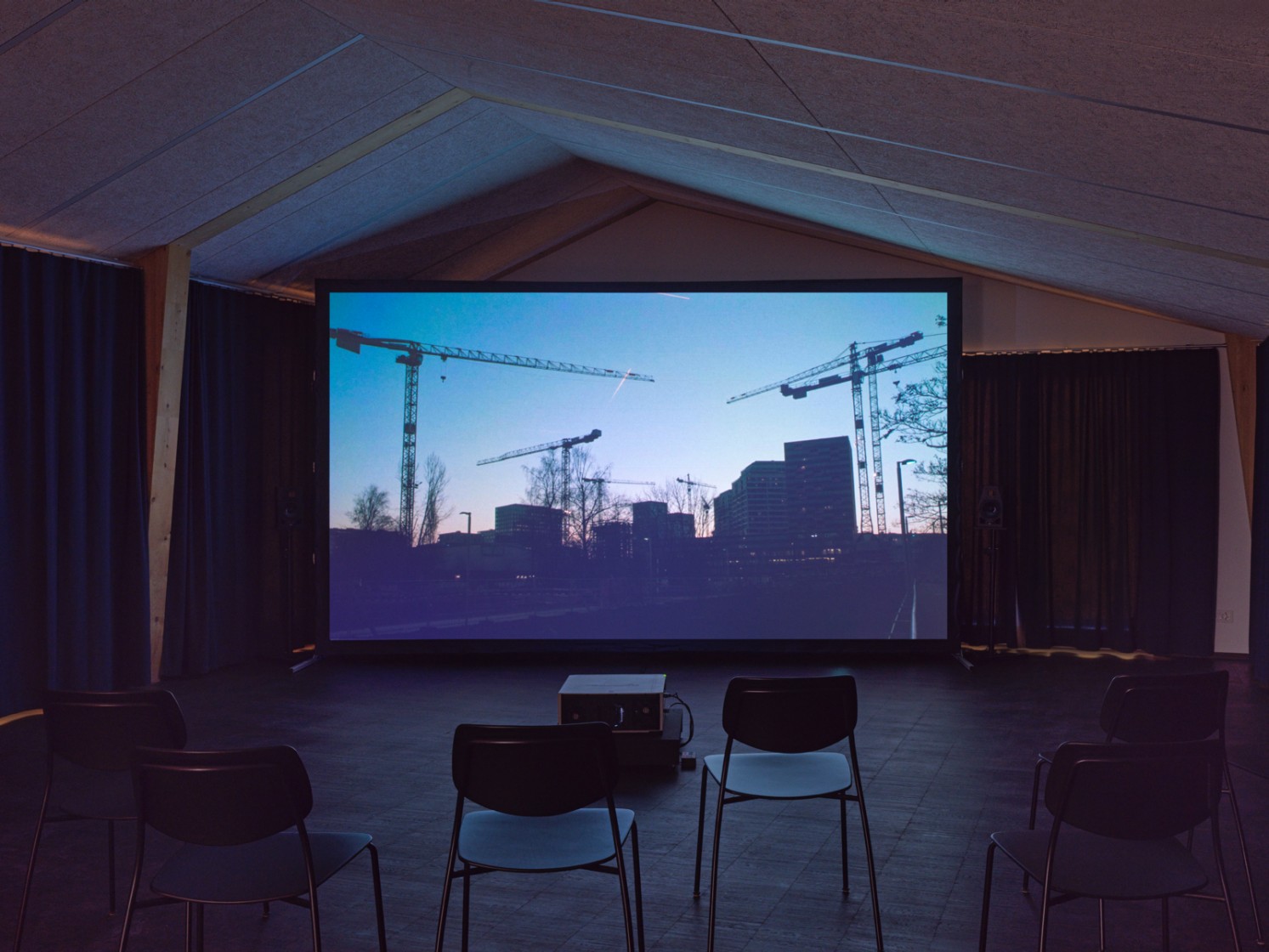 Filminstallation mit zwei Stühlen und Beamer, Filmstill einer Baustellensituation 