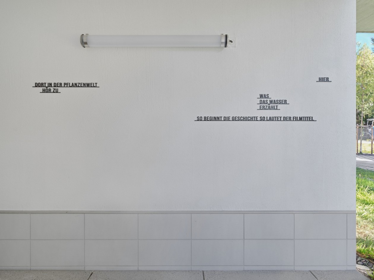 Hausfassade mit künstlerischer Textinstallation und Beleuchtung