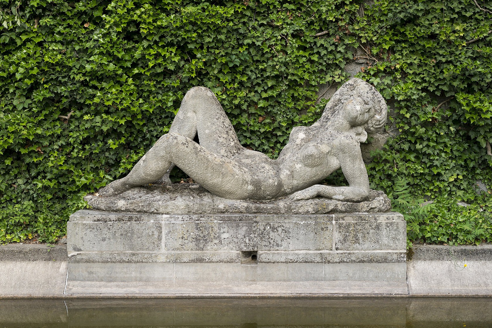 Skulptur einer liegenden Frau beim Wasserbecken