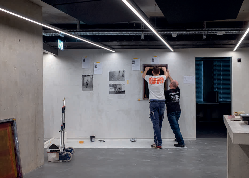 zwei Personen, die an einer Betonwand einen Siebdruck anbringen