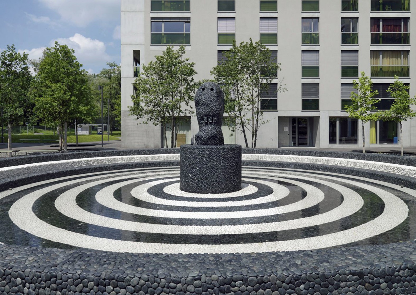 Skulptur in der Mitte eines Brunnens mit konzentrischen Kreisen