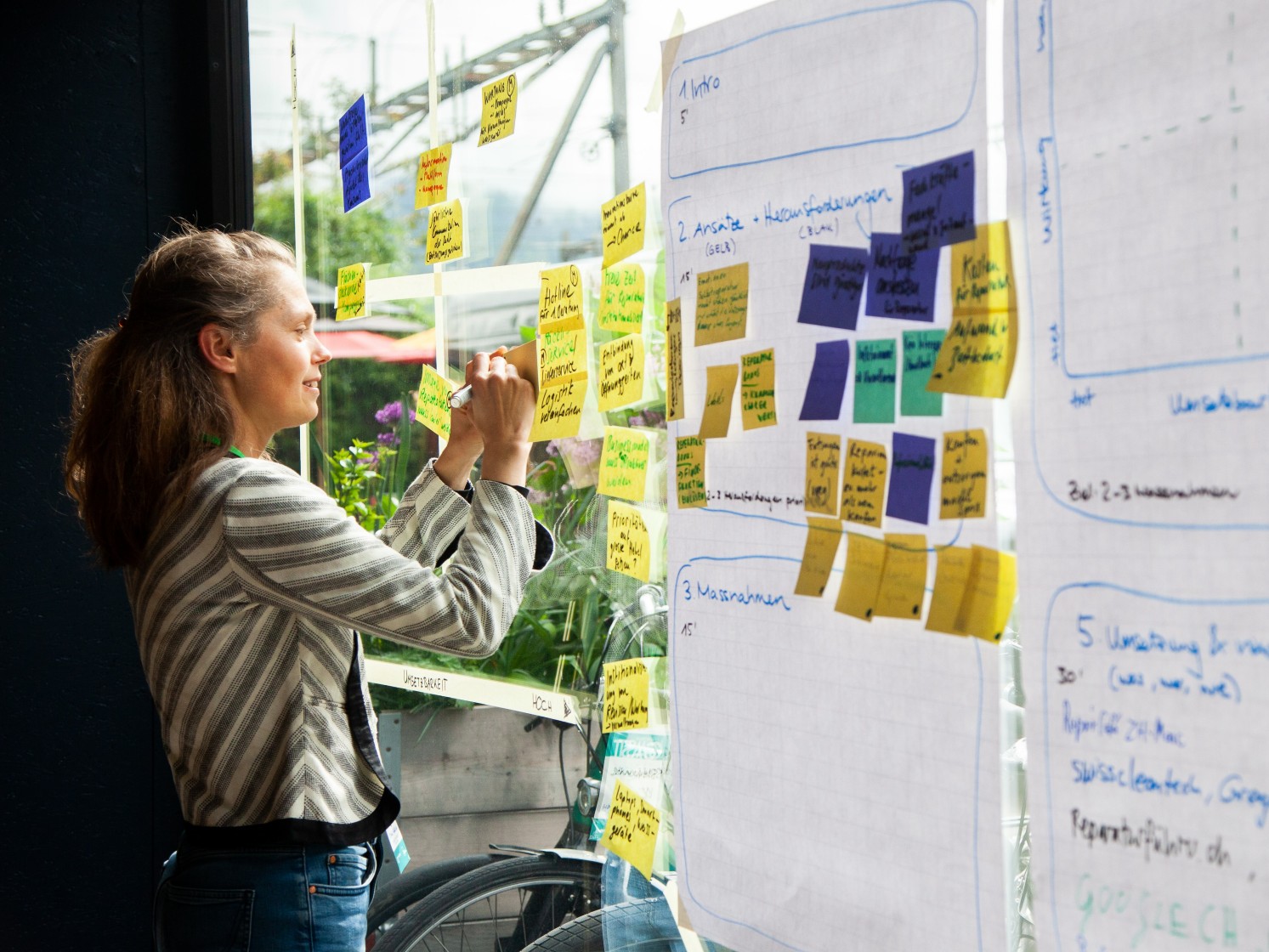 Frau notiert Idee auf Post-it