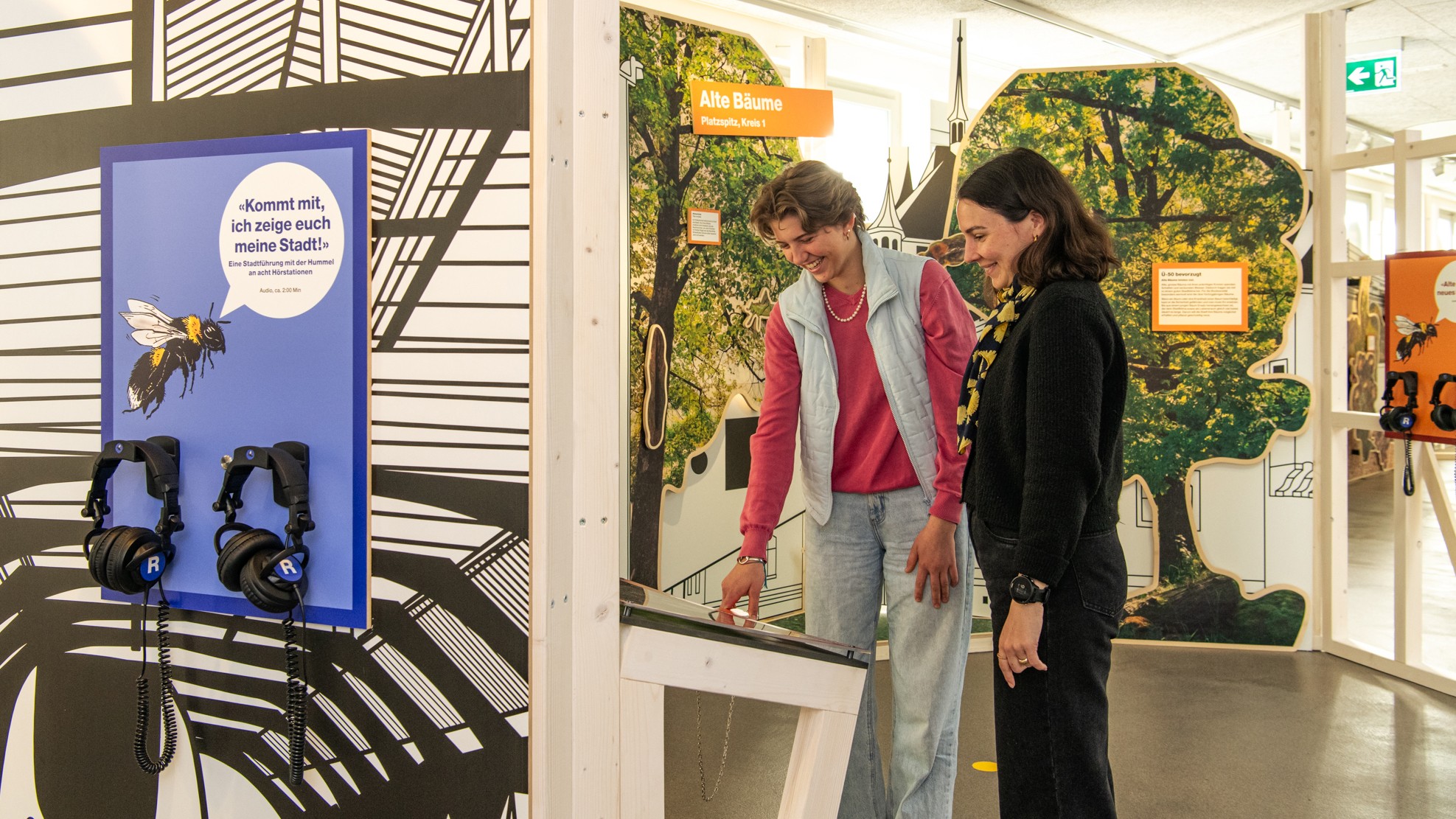 Im Ausstellungsraum in der Stadtgärtnerei sind zwei Besucherinnen an einer Station.