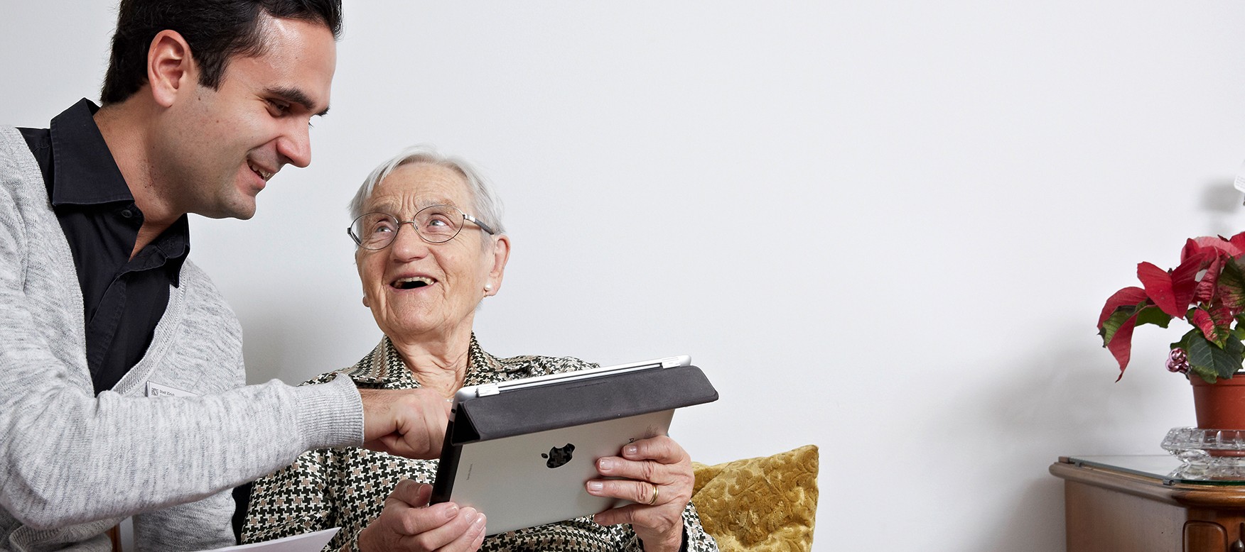 Ein Mann zeigt einer Seniorin etwas auf dem iPad