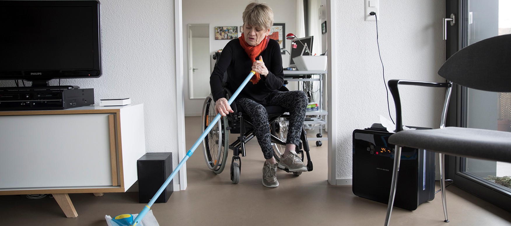 Eine Frau im Rollstuhl reinigt den Boden